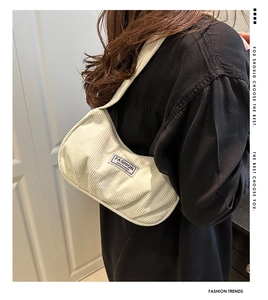 Detail of off-white corduroy shoulder bag with Fashion Instinct label worn by model