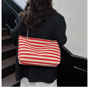Detail of red and white striped tote bag with elegant gold metal chain shoulder strap