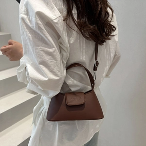 Dark brown minimalist leather handbag with silver hardware and adjustable strap on a model