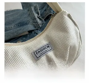 Close-up of off-white corduroy texture with Fashion Instinct label on underarm bag