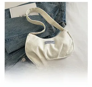 Detail of off-white corduroy underarm bag featuring pleated texture and fashion label