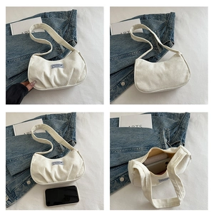 Detail view of white corduroy crescent bag showing internal storage and fashion patch