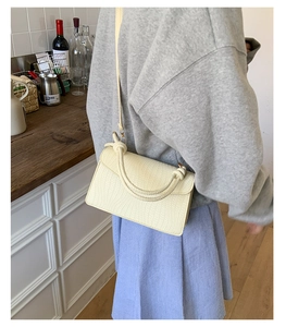 Vue détaillée du sac beige avec texture tissée et poignée avec détail de nœud
