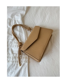 Détail du sac à bandoulière beige avec texture tissée, poignée corde et boucles dorées