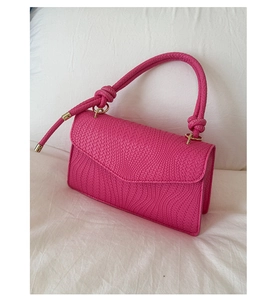 Gros plan du sac à main tissé fuchsia avec texture tressée et détail de poignée nouée