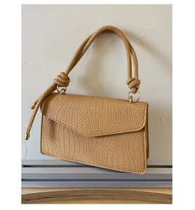 Détail du sac bandoulière tressé beige avec poignée nouée épaisse et finitions dorées