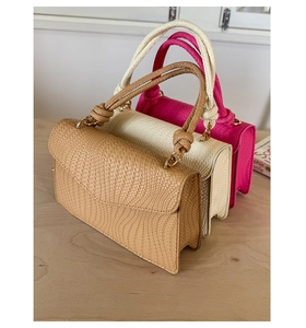 Détail de la texture tressée et de la poignée nouée sur des sacs marron, blanc et rose