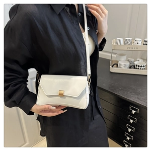 Dettaglio di una borsa a tracolla bianca minimalista con chiusura in metallo dorato rettangolare