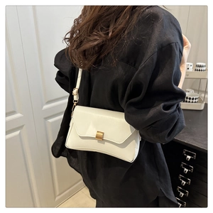 Borsa a tracolla bianca minimalista con fibbia dorata indossata su camicia nera