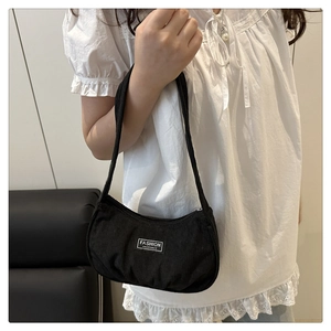 Detail of black corduroy shoulder bag with fashion instinct label worn by a model