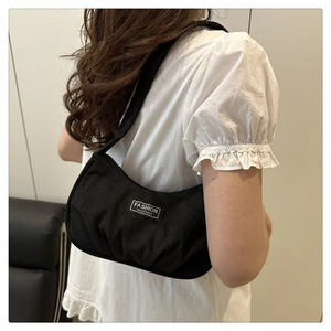 Detail of black corduroy shoulder bag with FASHION INSTINCT label on a white top