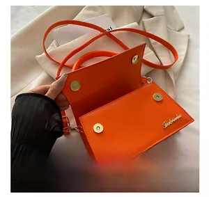 Detailweergave van feloranje schoudertas met magnetische gespen en binnenste structuur