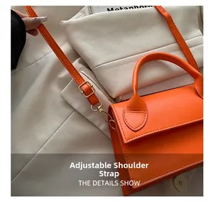 Detail van verstelbare lederen schouderriem op feloranje crossbodytas met gouden hardware