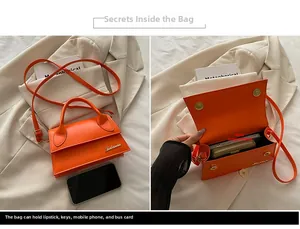 Detail of orange mini crossbody bag showing golden logo and internal main pocket capacity