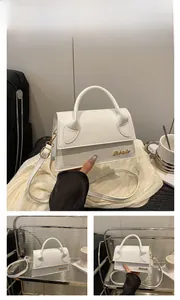 Detailed close-up of white PU leather crossbody bag with golden metal logo and top handle