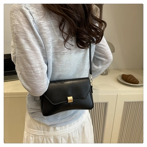 Dettaglio borsa a tracolla minimalista in pelle nera con elegante fibbia in oro opaco