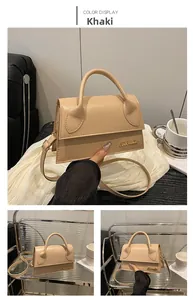 Detail view of khaki crossbody bag with smooth texture and golden logo accents