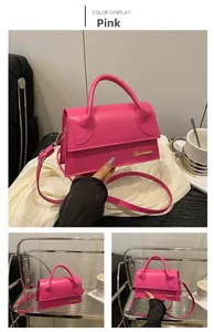 Detail of rose pink trapezoid handbag featuring gold letter logo and leather strap