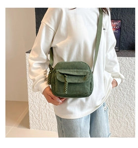 Detail of army green corduroy crossbody bag with hand-woven zipper pull on front pocket