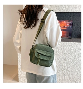 Detail of dark green corduroy crossbody bag with woven knot zipper and adjustable strap