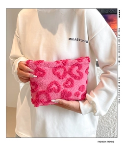 Borsa per cosmetici in peluche rosa con motivo a cuori tenuta da una modella