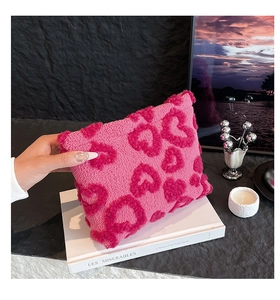Dettaglio della borsa di peluche rosa con cuori rossi su una base di libro