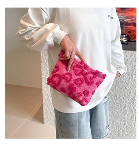 Close-up of pink plush makeup bag featuring a textured 3D heart pattern for travel