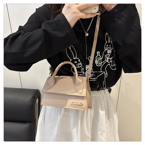 Detailopname van een minimalistische lichtbeige crossbodytas met merklogo-belettering