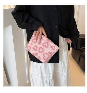Close-up of pink plush makeup bag featuring 3D embossed heart patterns and soft faux fur