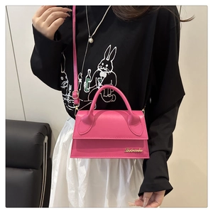 Détail du mini sac bandoulière rose avec poignée ronde et logo doré sur le cuir mat