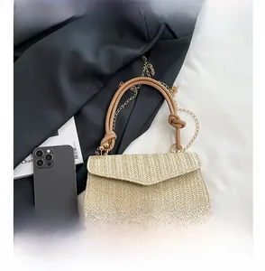 Détail du sac à main en paille tressée avec texture à chevrons et poignée en cuir