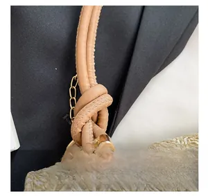 Gros plan du sac bandoulière tressé beige avec nœud en cuir et détails dorés
