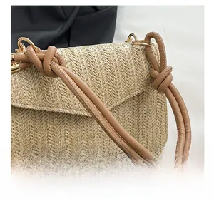 Détail du sac tressé en paille avec poignée marron nouée et chaîne en métal doré