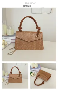 Détails d'un sac bandoulière en paille marron avec poignée nouée et chaîne dorée