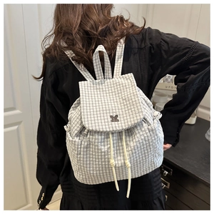 Rear view of black and white checkered backpack with drawstring and flap closure