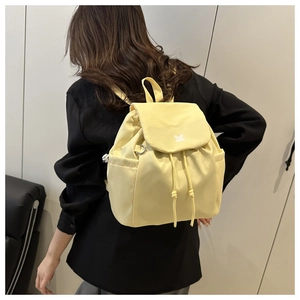 Rear view of a minimalist yellow drawstring backpack with side pockets on a model