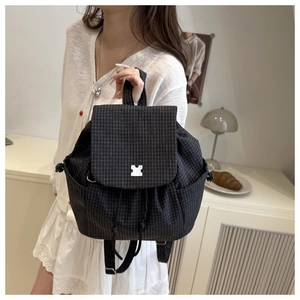 Close-up of black and white plaid backpack with drawstring closure and metal buckle