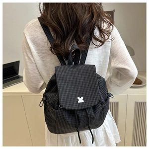 Detail of checkered drawstring backpack with puzzle logo showing fabric texture