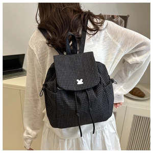 Detail of drawstring backpack with black and white check pattern and silver puzzle buckle