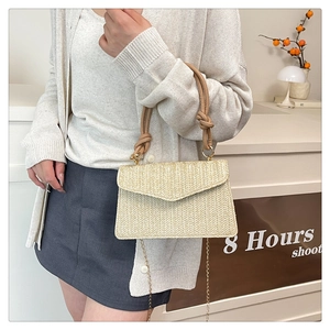 Détail du sac bandoulière en paille beige avec anses en corde marron et chaîne dorée