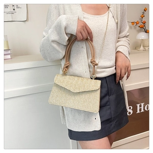 Détail d'un sac bandoulière tissé beige avec poignée en cuir et chaîne dorée