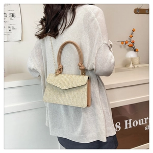 Détail du tissage en V du sac en paille naturelle avec poignée en cuir et chaîne dorée