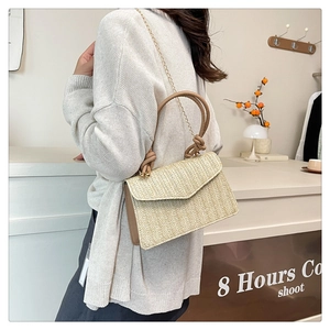 Détail du sac à main en paille tressée avec garniture en cuir brun et chaîne dorée