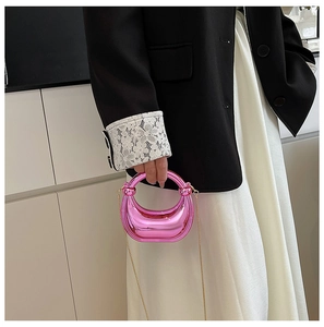Detalle de un bolso rosa metalizado brillante con acabado de espejo y cadena dorada