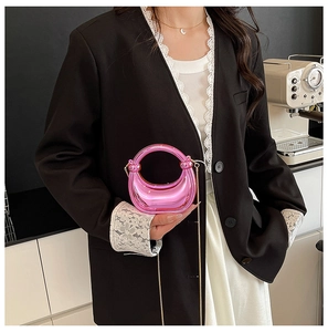 Detalle del mini bolso de media luna rosa metálico con elegante cadena dorada