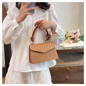 Détail du sac en paille tressée avec poignée en PU marron et chaîne dorée élégante