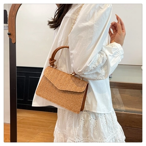 Détail du sac en paille tissée avec anse ronde en cuir foncé et nœud décoratif élégant