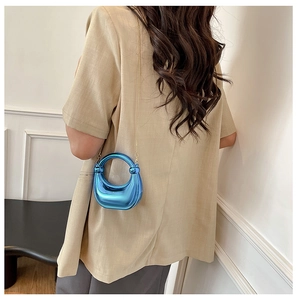 Primer plano del bolso media luna azul metalizado con asa circular y cadena dorada