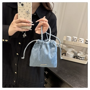 Détail du sac seau en denim bleu clair avec plaque JINGPIN et fermeture à cordon