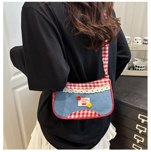 Detail of denim crossbody bag with red gingham trim and sweet cherry bear patch